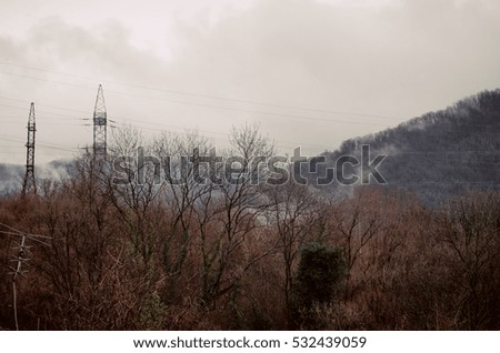 Mountain tops and electric poles, transmission in the fog. The highlands.