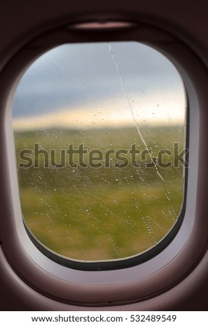 Water drops on window of airplane in rainy day while landing with blur background