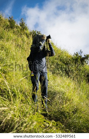young man taking photos in mountain valley with dslr camera