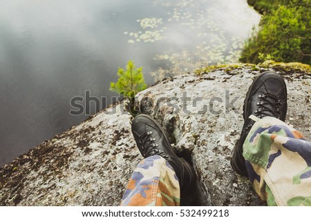 Male feet in camouflage pants and black rough shoes. Travel lifestyle background. Vintage tonal correction photo filter, old style