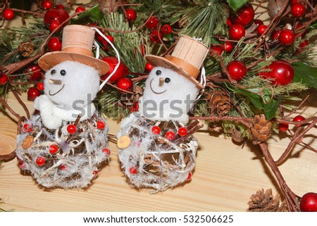 Two Christmas snowman with fir branches with red berries.