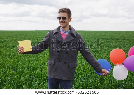 happy man holding colorful balloons and presents, celebrating events, in the green field, smiling and laughing, wearing sunglasses, happy time,surprise
