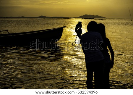 Happy young women enjoying vacation together having fun on the beach and taking selfie photo using smartphone camera
