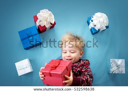Happy child on blue blanket. Cute boy with many presents