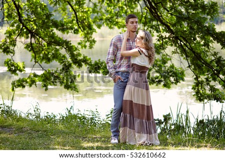 A loving couple walking by the lake outdoors summer sun warm beautiful