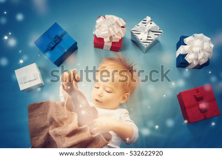 Happy child on blue blanket. Cute boy with many presents