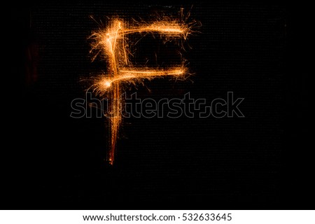 The English letter F made of sparklers on black background