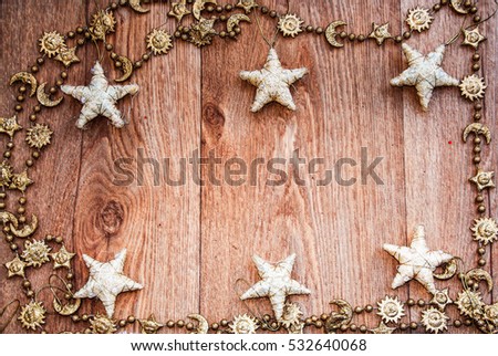 golden   christmas frame with a golden  chain and white texile stars on  wooden table 