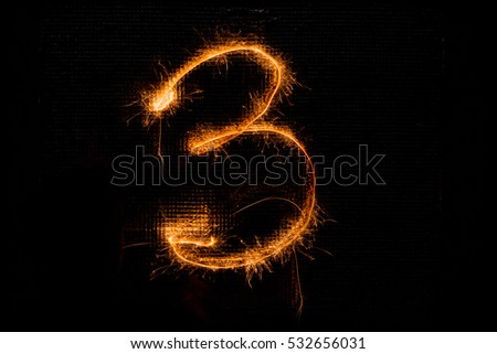 The number 3 made of sparklers on black background
