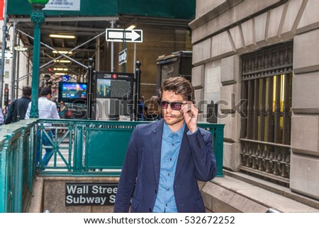 European Business Man traveling in New York. Dressing in blue suit, wearing sunglasses, young handsome man with beard confidently walking out from subway station, going to work. Color filtered effect.