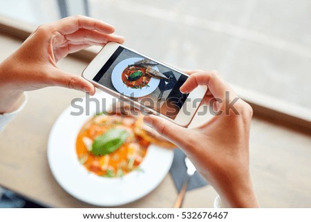 food, eating, technology, culinary and people concept - woman hands with smartphone photographing gazpacho soup at restaurant