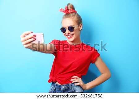 Young beautiful woman with smart phone on blue background