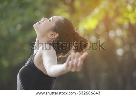 Freedom and happiness woman raise up her hand and deep breath with the sun lighting against green background. Royalty-Free Stock Photo #532686643