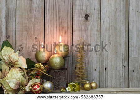 Christmas flowers, gold candles, red and gold ornaments, and gold Christmas tree with presents by antique rustic wood background; Christmas background collage with decorations