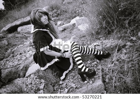 Beautiful asian girl dressed in gothic lolita sitting on a rock
