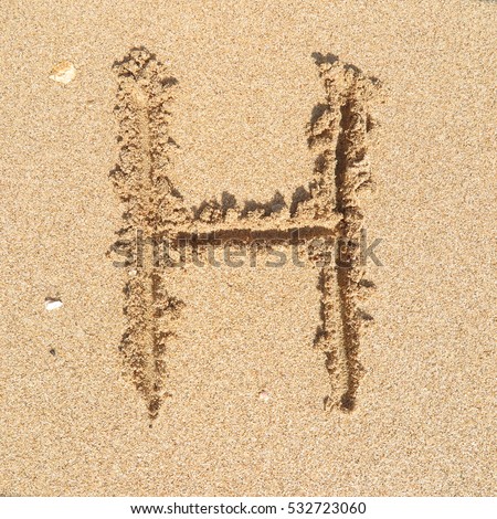 Handwriting english alphabet "H" on sand of beach Royalty-Free Stock Photo #532723060