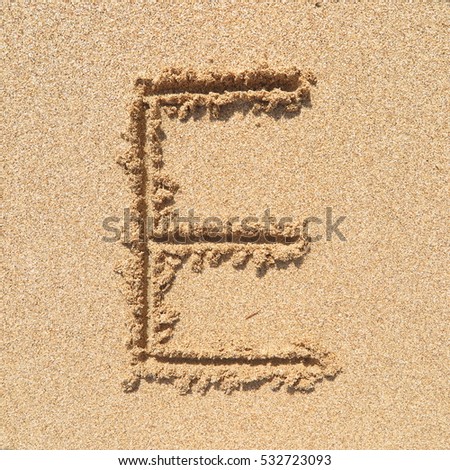 Handwriting english alphabet "E" on sand of beach