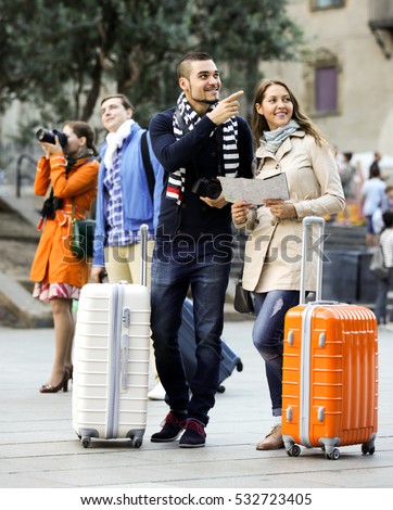 Portrait of attractive tourists with map and baggage in European city. Focus on the right couple