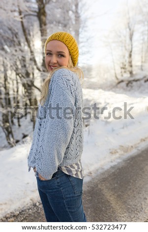 Winter portrait of a young smiling woman in a yellow hat on a background sunset. Winter day