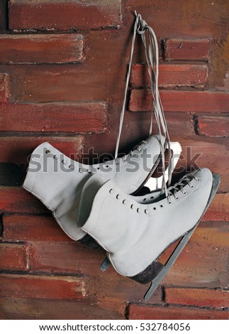 White skates hanging on a brick wall