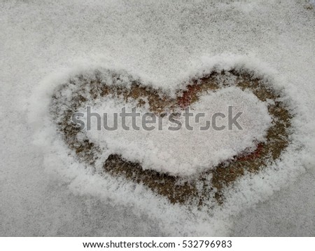 Drawing hearts in the snow. Snow heart shape. Heart on the snow closeup. 
