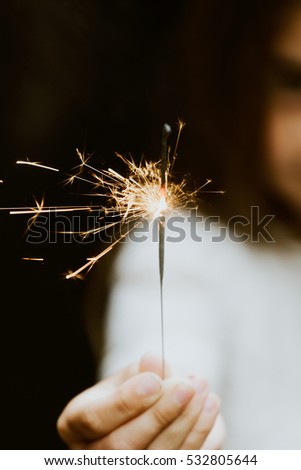 little girl holding fireworks on black background