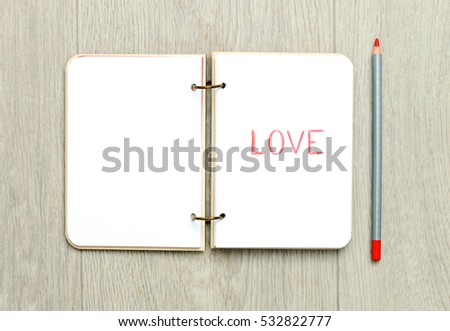 Opened blank notepad with drawn word LOVE on wooden table