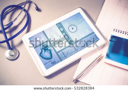 White tablet pc and doctor tools on gray surface Royalty-Free Stock Photo #532828384