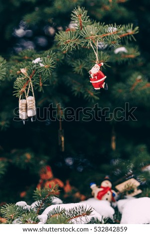 Closeup christmas tree decoration handmade miniature santa, small snowman with wooden sled, and ice skates on the branch