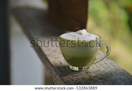 Vintage tone closeup small glass shot with milk and green tea form light window focus one point shallow with depth of field on wooden background