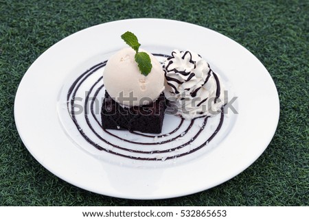 Brownies and vanilla ice cream with whipped cream on white plate