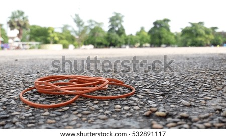 Rubber bands on the ground with park background.