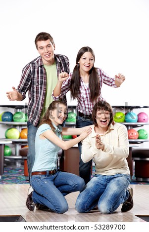 Four young friends rejoice to a successful throw in bowling