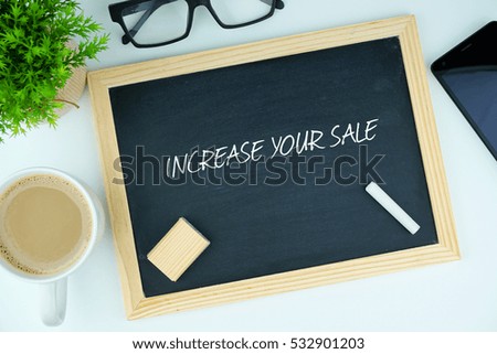 Top or flat lay view of chalkboard written with INCREASE YOUR SALE inscription. A cup of coffee, small green tree on vase, spectacle and smart phone on white modern table. Business conceptual.