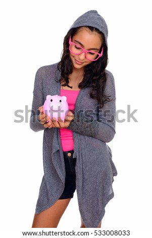 Studio shot of young beautiful Caucasian teenage girl holding piggy bank isolated against white background