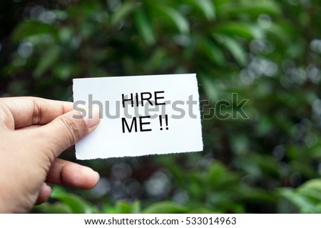 Close up of hands holding white card with HIRE ME!! sign written