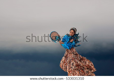 attractive young woman with tambourine outdoors. One minute before storm Royalty-Free Stock Photo #533031310