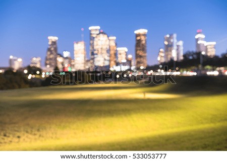 Blurred abstract with bokeh light downtown Houston illuminated at blue hour with green park lawn and modern skylines light. It is the most populous city in Texas and the fourth-most in United States.