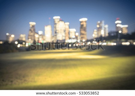 Blurred abstract with bokeh light downtown Houston illuminated at blue hour with green park lawn and modern skylines light. The most populous city in Texas and the fourth-most in America. Vintage tone