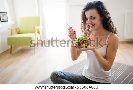 Woman eating healthy salad after working out at home Royalty-Free Stock Photo #533084080
