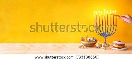 Image of jewish holiday Hanukkah with menorah (traditional Candelabra), donut and wooden dreidel (spinning top)

