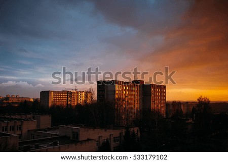Amazing sunset over the city. Blue and orange sky. Reflection in the windows of houses