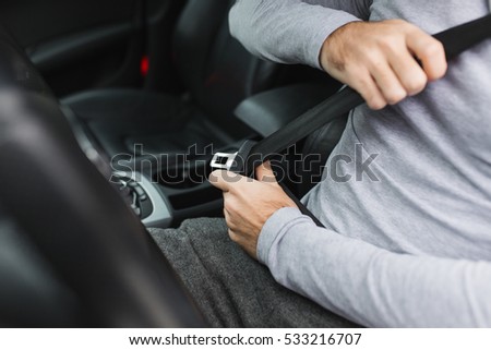 Closeup of man fastening seat belt in car Royalty-Free Stock Photo #533216707