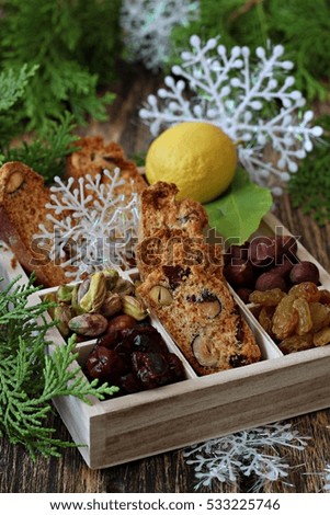 Biscotti made of nuts and raisin in a box filled with hazelnut , pistachio and cranberry - Christmas background with snowflake 