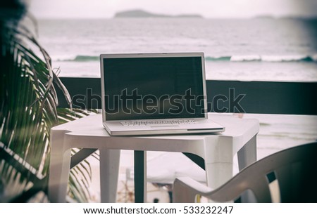 Computer on table outside on apartment balcony. Vacation workplace for laptop in tropical beach resort for modern digital nomad lifestyle blog, freelancer business website, image with filter effect