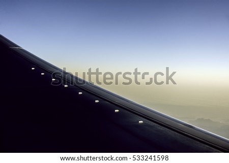 Row of eight vortex generators, which increase wing performance and efficiency, in sunlight on leading edge of wing on a commercial aircraft in flight, for themes of aviation, engineering, and design Royalty-Free Stock Photo #533241598