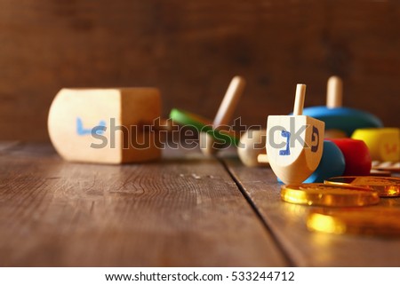 Image of jewish holiday Hanukkah with wooden dreidels colection (spinning top) and chocolate coins on the table

