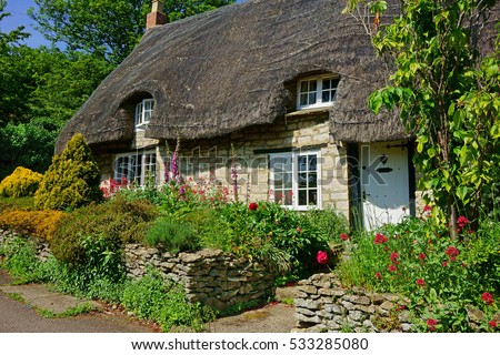 A beautiful quaint Cotswold country Thatched Cottage and garden in summer in the heart of The Cotswolds, Gloucestershire, United Kingdom Royalty-Free Stock Photo #533285080