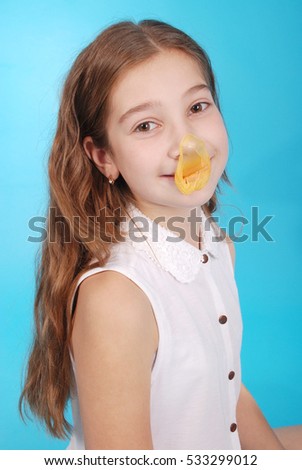 Young girl playing with chewing gum isolated on blue