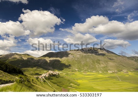 Famous mountain village of Castelluccio di Norcia with beautiful summer landscape at Piano Grande (Great Plain) mountain plateau in the Apennine Mountains on a sunny day, Umbria, Italy